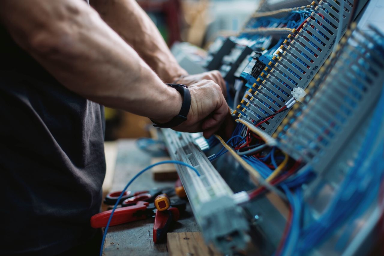 Hands, cables and terminal blocks inside an electrical cabinet