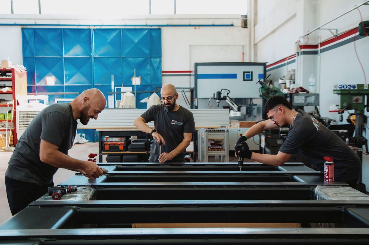 Tre persone montano un basamento in officina