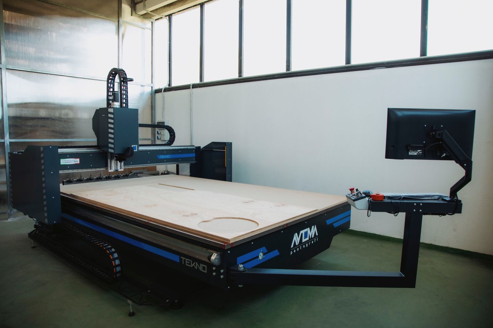 La TEKNO nel capannone, con il monitor su braccio e il piano in legno