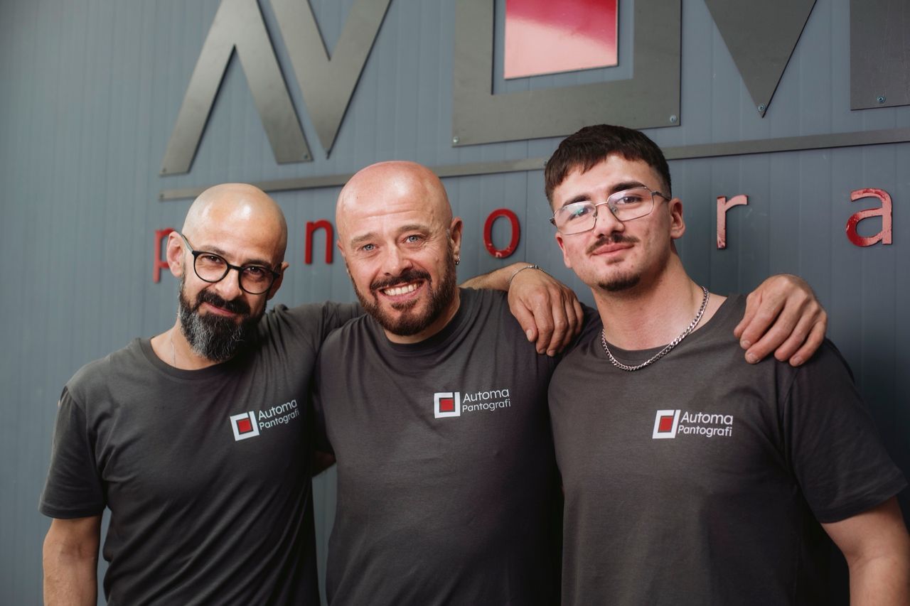 Three technicians together in front of the Automa logo