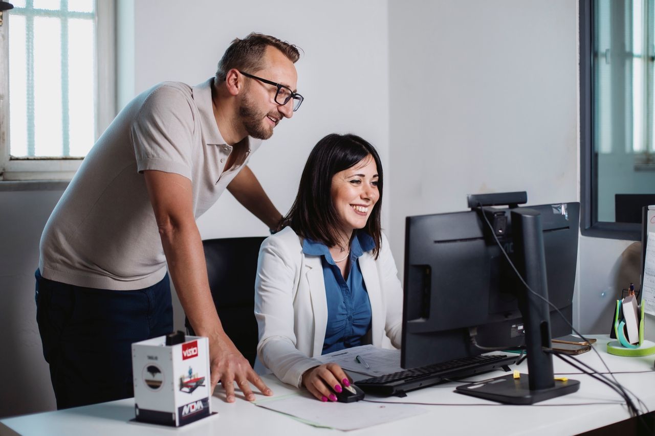 A colleague assisting an office employee at the computer